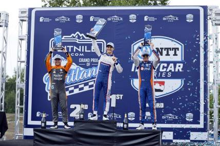 Sep 3, 2023; Portland, Oregon, USA; NTT Indy Car driver Alex Palou (center) lifts his first place trophy with second place finisher Felix Rosenqvist (left) and third place finisher Scott Dixon (right) at Portland International Raceway. Mandatory Credit: Soobum Im-USA TODAY Sports