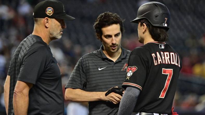 Sep 6, 2023; Phoenix, Arizona, USA; Arizona Diamondbacks left fielder Corbin Carroll (7) has his hand examined by a trainer as manager Torey Lovullo (17) looks on in the fourth inning against the Colorado Rockies at Chase Field. Mandatory Credit: Matt Kartozian-USA TODAY Sports