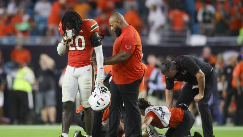 Sep 9, 2023; Miami Gardens, Florida, USA; Miami Hurricanes safety James Williams (20) reacts as trainers check on Miami Hurricanes safety Kamren Kinchens (5) after an injury against the Texas A&M Aggies during the fourth quarter at Hard Rock Stadium. Mandatory Credit: Sam Navarro-USA TODAY Sports