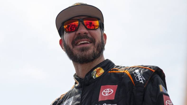 Sep 10, 2023; Kansas City, Kansas, USA; NASCAR Cup Series driver Martin Truex Jr. (19) smiles on the grid before the NASCAR Cup Series Hollywood Casino 400 at Kansas Speedway. Mandatory Credit: Amy Kontras-USA TODAY Sports