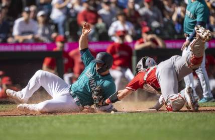 Sep 13, 2023; Seattle, Washington, USA; Seattle Mariners second baseman Ty France (23) slides safely into home plate to score a run against Los Angeles Angels catcher Logan O'Hoppe (14) during the fifth inning at T-Mobile Park. Mandatory Credit: Stephen Brashear-USA TODAY Sports
