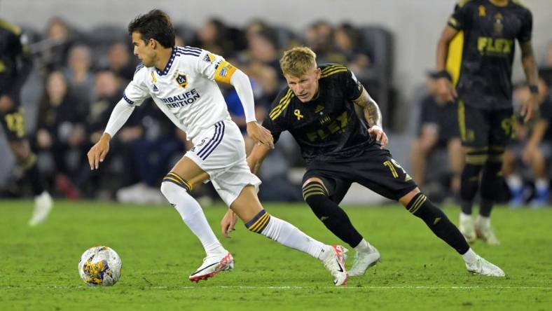 Sep 16, 2023; Los Angeles, California, USA; Los Angeles Galaxy midfielder Riqui Puig (6) keeps the ball from Los Angeles FC midfielder Mateusz Bogusz (19) in the second half at BMO Stadium. Mandatory Credit: Jayne Kamin-Oncea-USA TODAY Sports