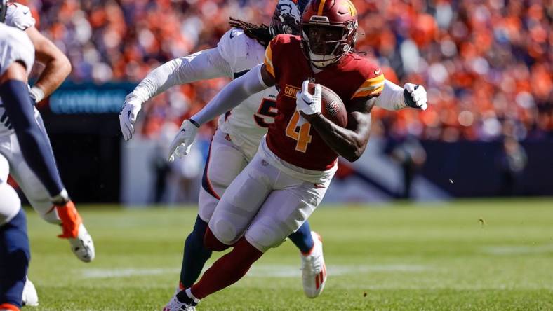 Sep 17, 2023; Denver, Colorado, USA; Washington Commanders wide receiver Curtis Samuel (4) runs the ball ahead of Denver Broncos linebacker Randy Gregory (5) in the second quarter at Empower Field at Mile High. Mandatory Credit: Isaiah J. Downing-USA TODAY Sports