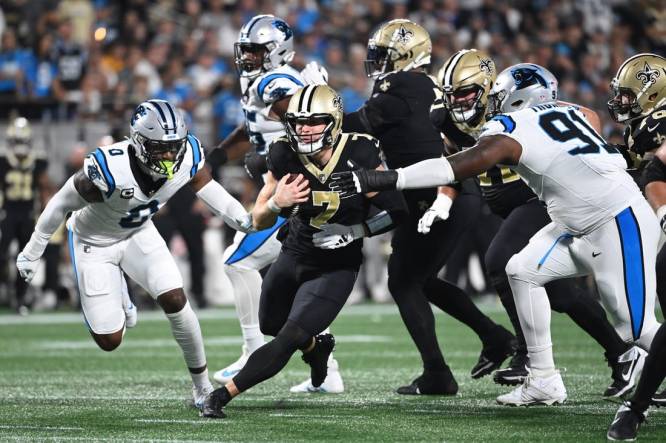 Sep 18, 2023; Charlotte, North Carolina, USA; New Orleans Saints quarterback Taysom Hill (7) with the ball as Carolina Panthers linebacker Brian Burns (0) and defensive end Nick Thurman (91) defend in the first quarter at Bank of America Stadium. Mandatory Credit: Bob Donnan-USA TODAY Sports