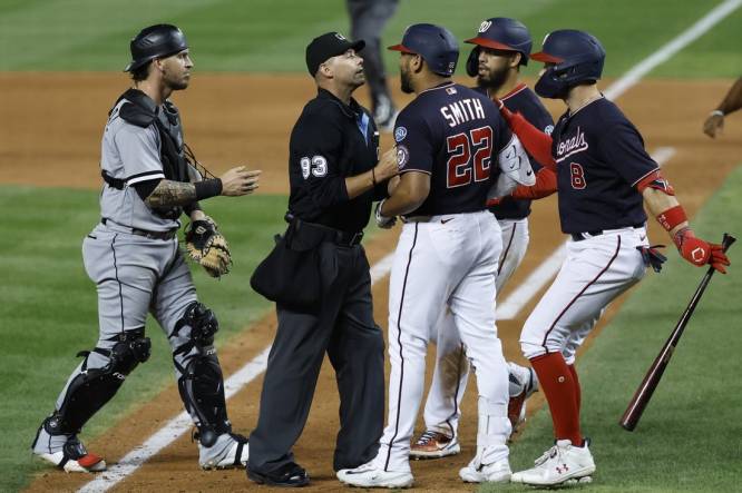Sep 18, 2023; Washington, District of Columbia, USA; Washington Nationals first baseman Dominic Smith (22) is restrained from Chicago White Sox starting pitcher Mike Clevinger (not pictured) after hitting a home run by home plate umpire Will Little (93) as White Sox catcher Yasmani Grandal (24) steps in during the ninth inning at Nationals Park. Mandatory Credit: Geoff Burke-USA TODAY Sports