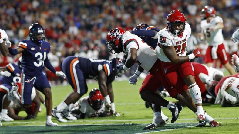 Sep 22, 2023; Charlottesville, Virginia, USA; North Carolina State Wolfpack running back Delbert Mimms III (34) scores a touchdown against the Virginia Cavaliers during the second quarter at Scott Stadium. Mandatory Credit: Geoff Burke-USA TODAY Sports