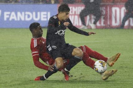 Sep 23, 2023; Washington, District of Columbia, USA; D.C. United Gabriel Pirani (10) is tackled by New York Red Bulls defender Andr s Reyes (4) while dribbling the ball in the box in the first half at Audi Field. Mandatory Credit: Geoff Burke-USA TODAY Sports