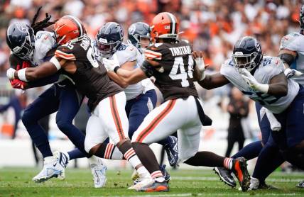 Cleveland Browns tight end David Njoku (85) tackles Tennessee Titans running back Derrick Henry (22) during the first quarter in Cleveland, Ohio, Sunday, Sept. 24, 2023.