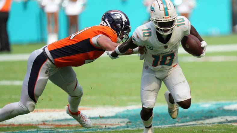 Miami Dolphins wide receiver Tyreek Hill (10) eludes the tackle of Denver Broncos linebacker Drew Sanders (41) in the third quarter of an NFL game at Hard Rock Stadium in Miami Gardens, Sept. 24, 2023.