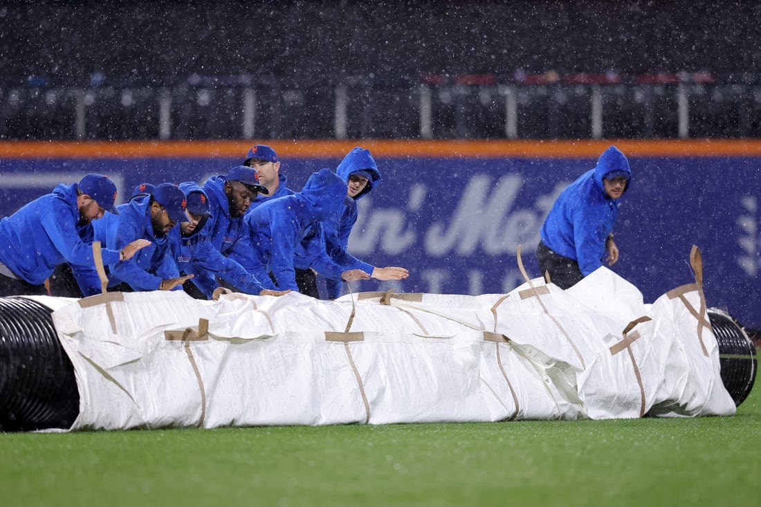 Sep 28, 2023; New York City, New York, USA; New York Mets grounds crew roll out the tarp during a rain delay during the ninth inning against the Miami Marlins at Citi Field. Mandatory Credit: Brad Penner-USA TODAY Sports