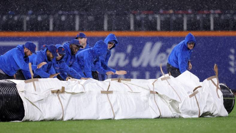 Sep 28, 2023; New York City, New York, USA; New York Mets grounds crew roll out the tarp during a rain delay during the ninth inning against the Miami Marlins at Citi Field. Mandatory Credit: Brad Penner-USA TODAY Sports