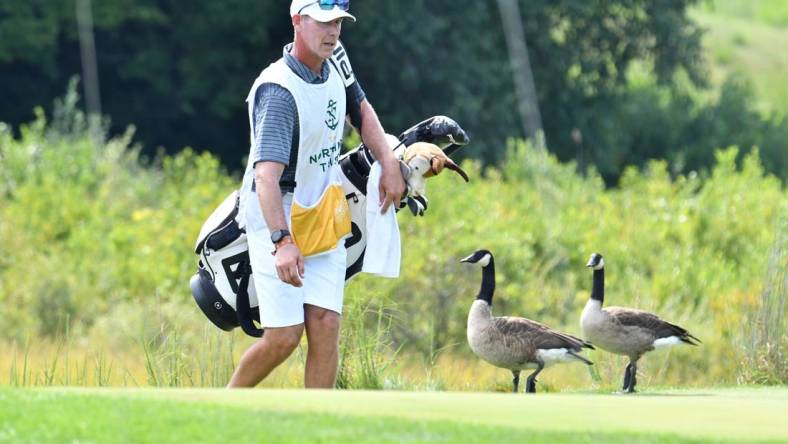 Aug 23, 2020; Norton, Massachusetts, USA; Caddie Phillip Lowe tries to shoo geese off the 2nd green at TPC of Boston. Mandatory Credit: Mark Konezny-USA TODAY Sports