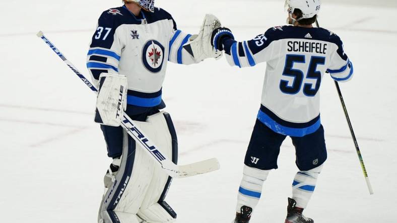 Apr 15, 2021; Toronto, Ontario, CAN; Winnipeg Jets forward Mark Scheifele (55) congratulates goaltender Connor Hellebuyck (37) on a win over the Toronto Maple Leafs during the third period at Scotiabank Arena. Mandatory Credit: John E. Sokolowski-USA TODAY Sports