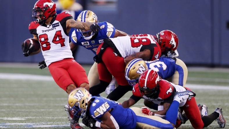 Aug 25, 2022; Winnipeg, Manitoba, CAN;  Calgary Stampeders wide receiver Reggie Begelton (84) is tackled by Winnipeg Blue Bombers defensive back Jamal Parker (45) during the first half at IG Field. Mandatory Credit: Bruce Fedyck-USA TODAY Sports