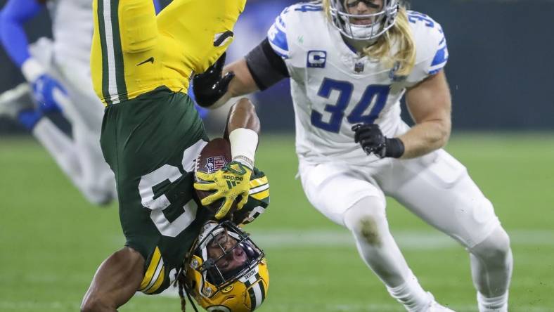 Sep 28, 2023; Green Bay, Wisconsin, USA; Green Bay Packers running back Aaron Jones (33) is upended against the Detroit Lions during their football game on Thursday, September 28, 2023, at Lambeau Field in Green Bay, Wis. Mandatory Credit: Tork Mason-USA TODAY Sports