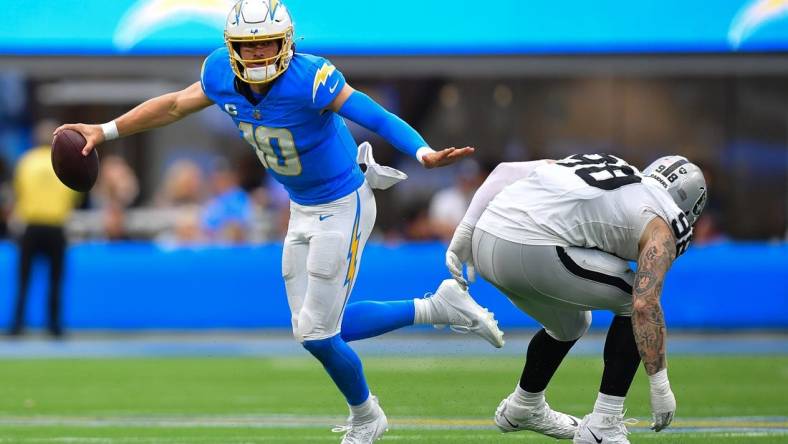 Oct 1, 2023; Inglewood, California, USA; Los Angeles Chargers quarterback Justin Herbert (10) moves the ball against Las Vegas Raiders defensive end Maxx Crosby (98) during the first half at SoFi Stadium. Mandatory Credit: Gary A. Vasquez-USA TODAY Sports