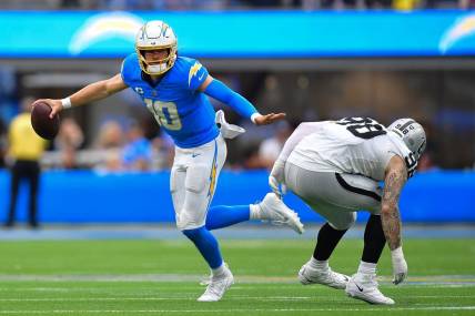 Oct 1, 2023; Inglewood, California, USA; Los Angeles Chargers quarterback Justin Herbert (10) moves the ball against Las Vegas Raiders defensive end Maxx Crosby (98) during the first half at SoFi Stadium. Mandatory Credit: Gary A. Vasquez-USA TODAY Sports