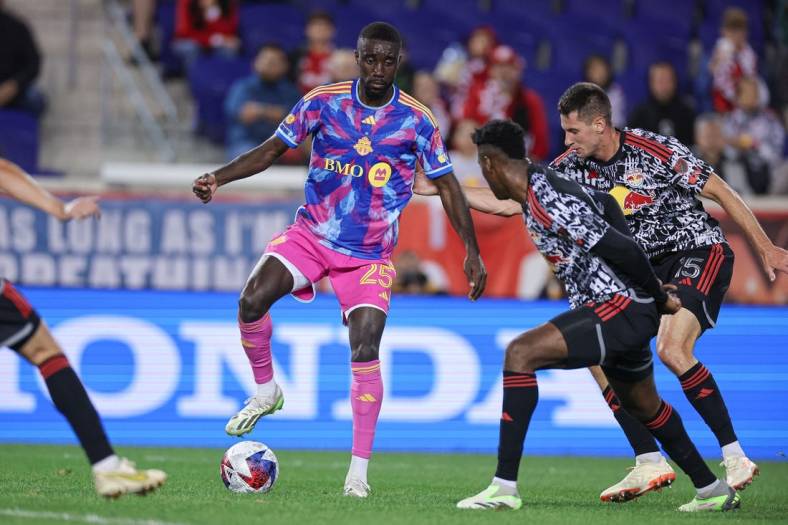 Oct 7, 2023; Harrison, New Jersey, USA; Toronto FC forward Prince Osei Owusu (25) controls the ball as New York Red Bulls defender Hassan Ndam (98) and defender Sean Nealis (15) defend during the first half at Red Bull Arena. Mandatory Credit: Vincent Carchietta-USA TODAY Sports