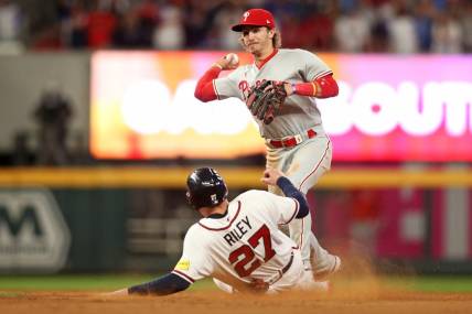 Oct 7, 2023; Cumberland, Georgia, USA; Philadelphia Phillies second baseman Bryson Stott (5) turns a double play over Atlanta Braves third baseman Austin Riley (27) during the eighth inning during game one of the NLDS for the 2023 MLB playoffs at Truist Park. Mandatory Credit: Brett Davis-USA TODAY Sports