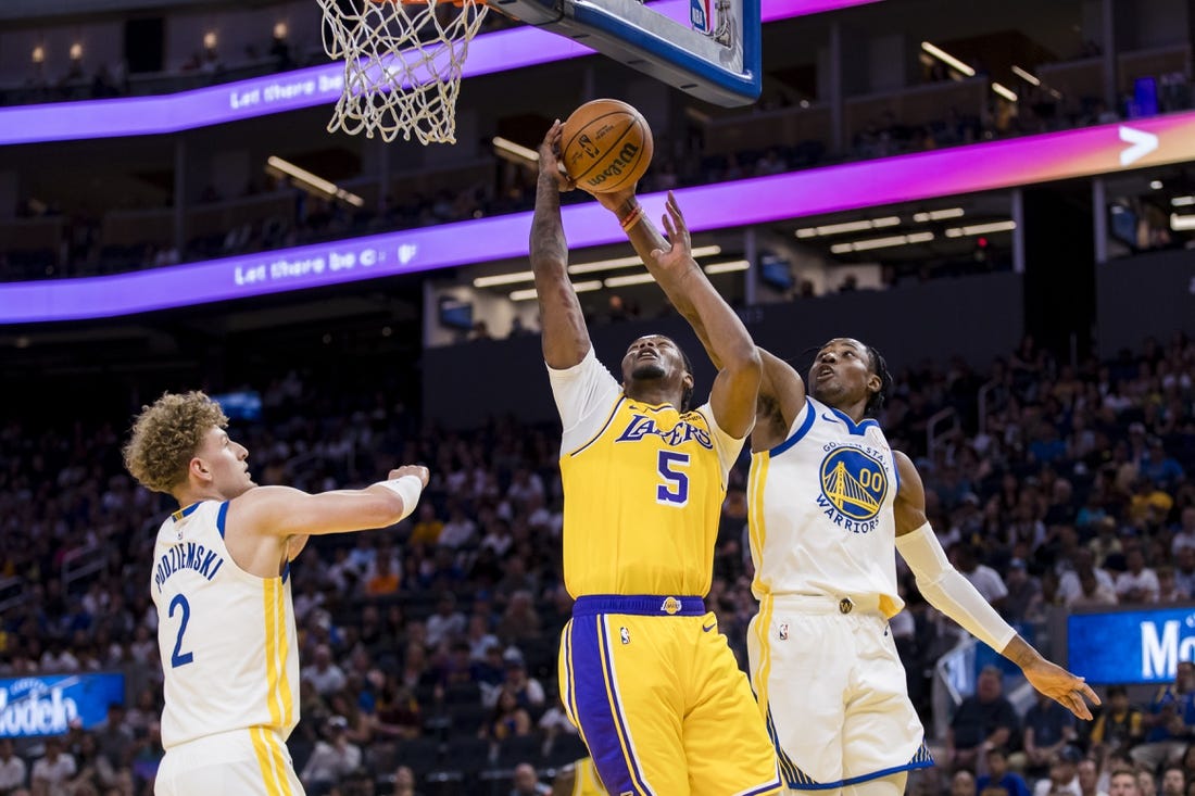 Oct 7, 2023; San Francisco, California, USA; Golden State Warriors guard Brandin Podziemski (2) and forward Jonathan Kuminga (00) defend Los Angeles Lakers forward Cam Reddish (5) during the first half at Chase Center. Mandatory Credit: John Hefti-USA TODAY Sports