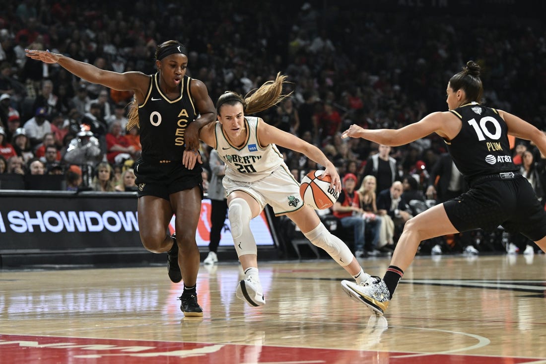 Oct 8, 2023; Las Vegas, Nevada, USA; New York Liberty guard Sabrina Ionescu (20) drives past Las Vegas Aces guard Jackie Young (0) and guard Kelsey Plum (10) in the first half during game one of the 2023 WNBA Finals at Michelob Ultra Arena. Mandatory Credit: Candice Ward-USA TODAY Sports