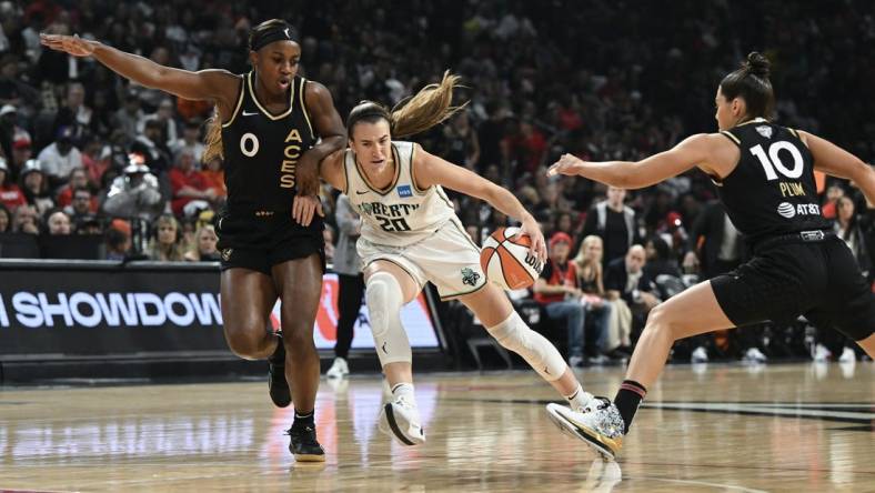 Oct 8, 2023; Las Vegas, Nevada, USA; New York Liberty guard Sabrina Ionescu (20) drives past Las Vegas Aces guard Jackie Young (0) and guard Kelsey Plum (10) in the first half during game one of the 2023 WNBA Finals at Michelob Ultra Arena. Mandatory Credit: Candice Ward-USA TODAY Sports