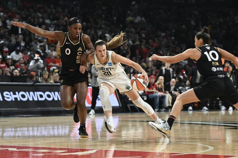 Oct 8, 2023; Las Vegas, Nevada, USA; New York Liberty guard Sabrina Ionescu (20) drives past Las Vegas Aces guard Jackie Young (0) and guard Kelsey Plum (10) in the first half during game one of the 2023 WNBA Finals at Michelob Ultra Arena. Mandatory Credit: Candice Ward-USA TODAY Sports