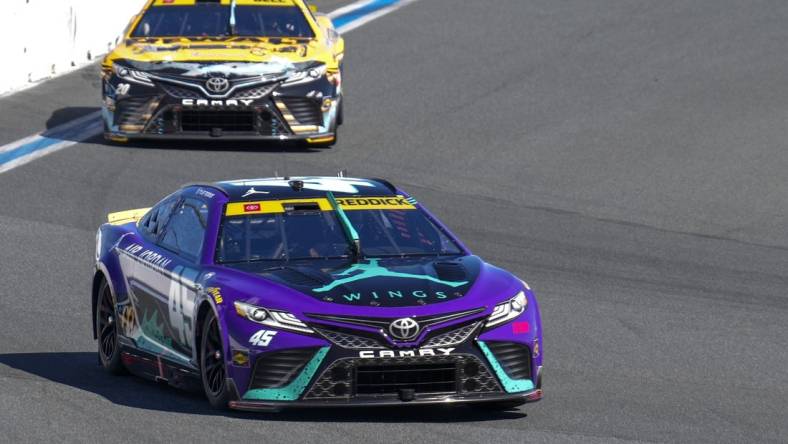 Oct 8, 2023; Concord, North Carolina, USA;  NASCAR Cup Series driver Tyler Reddick (45) leads driver Christopher Bell (20) out of turn eight during the Bank of America Roval 400 at Charlotte Motor Speedway Road Course. Mandatory Credit: Jim Dedmon-USA TODAY Sports