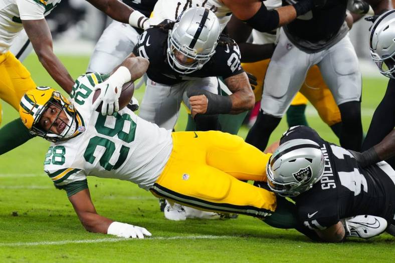 Oct 9, 2023; Paradise, Nevada, USA; Green Bay Packers running back AJ Dillon (28) is tackled by Las Vegas Raiders linebacker Robert Spillane (41) during the first quarter at Allegiant Stadium. Mandatory Credit: Stephen R. Sylvanie-USA TODAY Sports