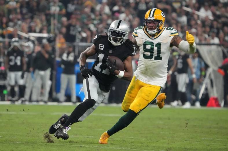 Oct 9, 2023; Paradise, Nevada, USA; Las Vegas Raiders wide receiver Davante Adams (17) is pursued by Green Bay Packers linebacker Preston Smith (91) in the second half at Allegiant Stadium. Mandatory Credit: Kirby Lee-USA TODAY Sports