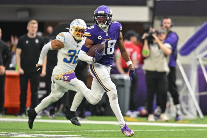 Sep 24, 2023; Minneapolis, Minnesota, USA; Minnesota Vikings wide receiver Justin Jefferson (18) scores on a touchdown pass as Los Angeles Chargers safety Alohi Gilman (32) chases from behind during the fourth quarter at U.S. Bank Stadium. Mandatory Credit: Jeffrey Becker-USA TODAY Sports