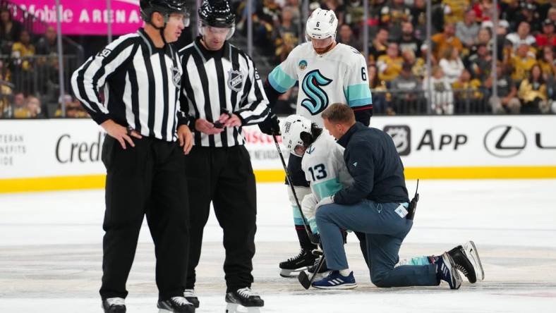 Oct 10, 2023; Las Vegas, Nevada, USA; Seattle Kraken left wing Brandon Tanev (13) is helped to his skates after sustaining an injury from a hit by Vegas Golden Knights center Brett Howden (not pictured) during the third period at T-Mobile Arena. Mandatory Credit: Stephen R. Sylvanie-USA TODAY Sports