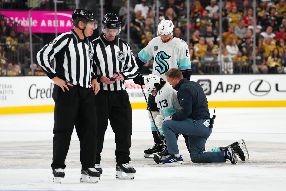 Oct 10, 2023; Las Vegas, Nevada, USA; Seattle Kraken left wing Brandon Tanev (13) is helped to his skates after sustaining an injury from a hit by Vegas Golden Knights center Brett Howden (not pictured) during the third period at T-Mobile Arena. Mandatory Credit: Stephen R. Sylvanie-USA TODAY Sports