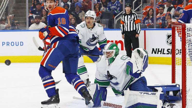 Oct 14, 2023; Edmonton, Alberta, CAN; Edmonton Oilers forward Zach Hyman (18) and Vancouver Canucks goaltender Casey DeSmith (29) look for a loose puck during the first period at Rogers Place. Mandatory Credit: Perry Nelson-USA TODAY Sports