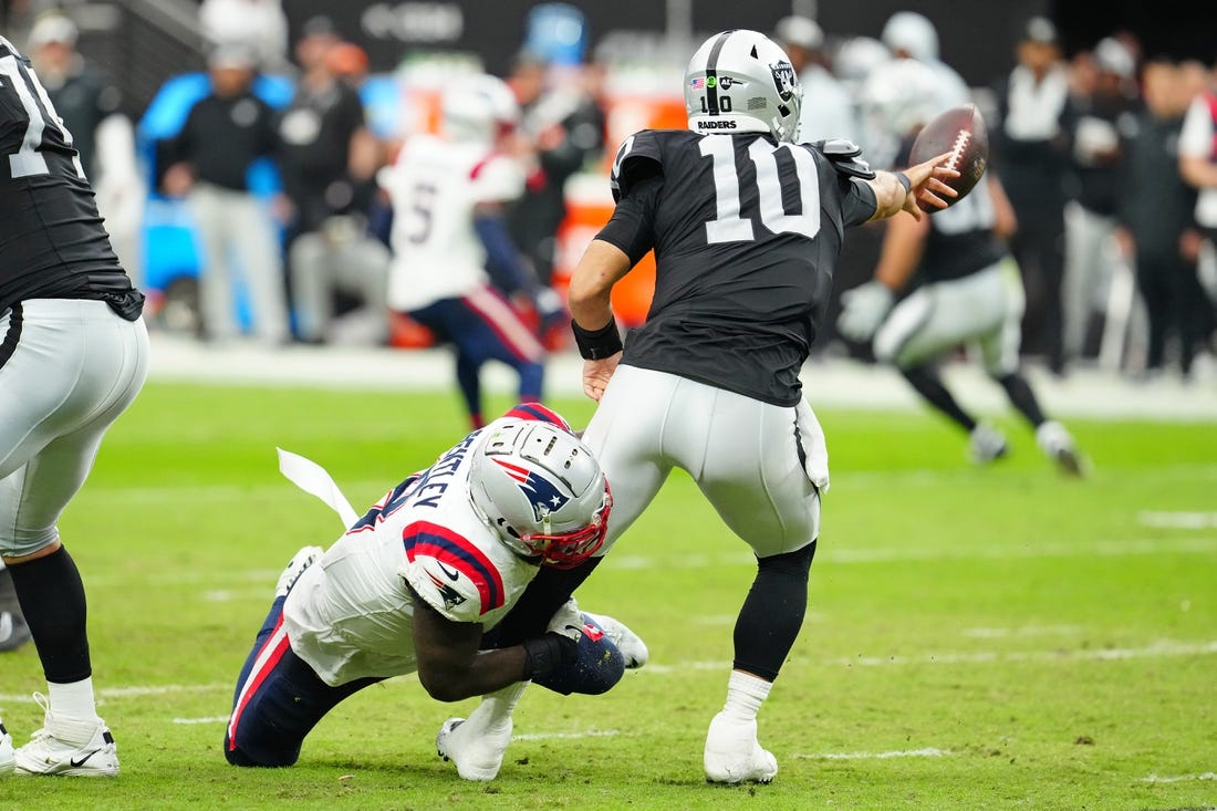 Oct 15, 2023; Paradise, Nevada, USA; Las Vegas Raiders quarterback Jimmy Garoppolo (10) flips the ball away to avoid being sacked by New England Patriots linebacker Ja'Whaun Bentley (8) during the second quarter at Allegiant Stadium. Mandatory Credit: Stephen R. Sylvanie-USA TODAY Sports