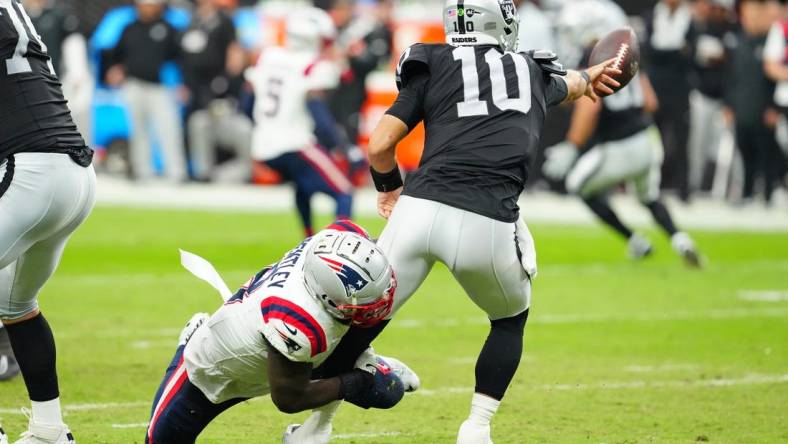 Oct 15, 2023; Paradise, Nevada, USA; Las Vegas Raiders quarterback Jimmy Garoppolo (10) flips the ball away to avoid being sacked by New England Patriots linebacker Ja'Whaun Bentley (8) during the second quarter at Allegiant Stadium. Mandatory Credit: Stephen R. Sylvanie-USA TODAY Sports