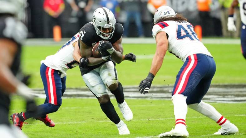 Oct 15, 2023; Paradise, Nevada, USA; Las Vegas Raiders running back Josh Jacobs (8) breaks through a hole against the New England Patriots during the first quarter at Allegiant Stadium. Mandatory Credit: Stephen R. Sylvanie-USA TODAY Sports