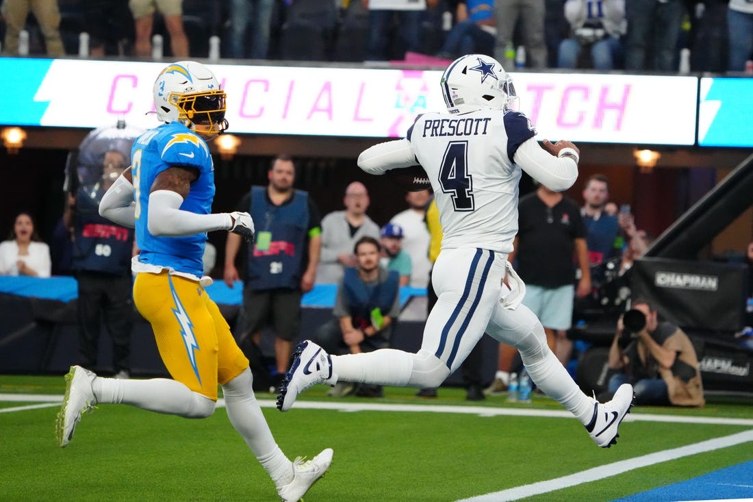 Oct 16, 2023; Inglewood, California, USA; Dallas Cowboys quarterback Dak Prescott (4) scores on an 18-yard touchdown run against Los Angeles Chargers safety Derwin James Jr. (3) in the first half at SoFi Stadium. Mandatory Credit: Kirby Lee-USA TODAY Sports