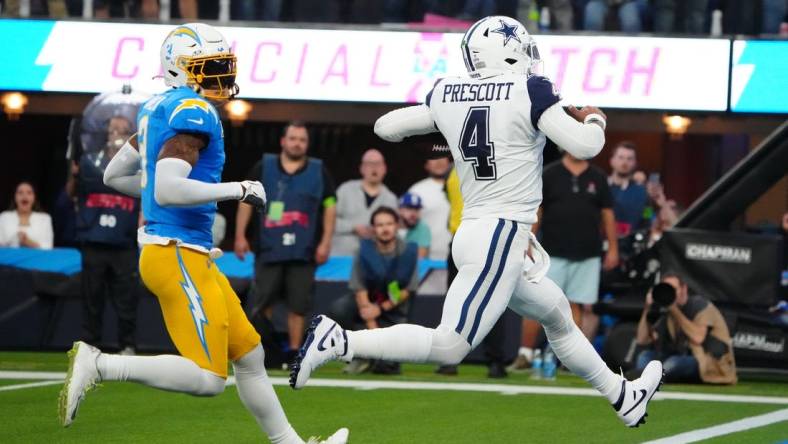 Oct 16, 2023; Inglewood, California, USA; Dallas Cowboys quarterback Dak Prescott (4) scores on an 18-yard touchdown run against Los Angeles Chargers safety Derwin James Jr. (3) in the first half at SoFi Stadium. Mandatory Credit: Kirby Lee-USA TODAY Sports