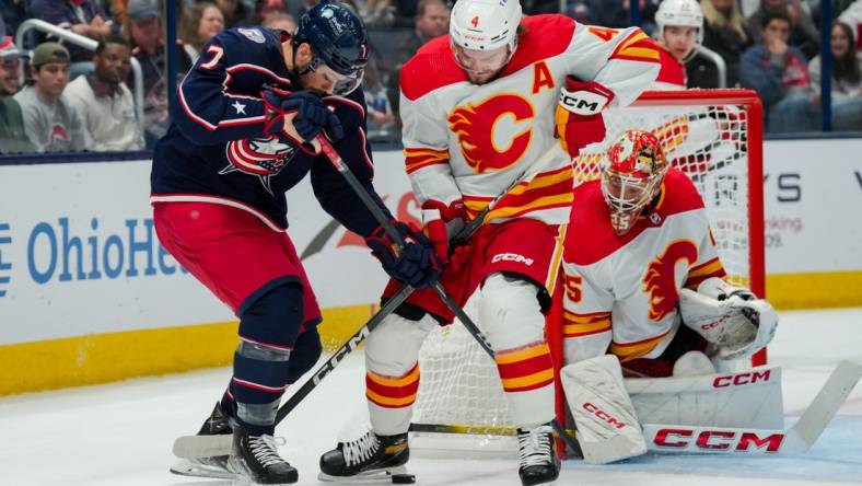 Oct 20, 2023; Columbus, Ohio, USA;  Columbus Blue Jackets center Sean Kuraly (7) battles for the puck against Calgary Flames defenseman Rasmus Andersson (4) in the first period at Nationwide Arena. Mandatory Credit: Aaron Doster-USA TODAY Sports