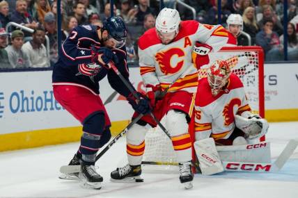 Oct 20, 2023; Columbus, Ohio, USA;  Columbus Blue Jackets center Sean Kuraly (7) battles for the puck against Calgary Flames defenseman Rasmus Andersson (4) in the first period at Nationwide Arena. Mandatory Credit: Aaron Doster-USA TODAY Sports