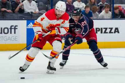 Oct 20, 2023; Columbus, Ohio, USA;  Calgary Flames defenseman Rasmus Andersson (4) skates with the puck against Columbus Blue Jackets right wing Patrik Laine (29) in the third period at Nationwide Arena. Mandatory Credit: Aaron Doster-USA TODAY Sports