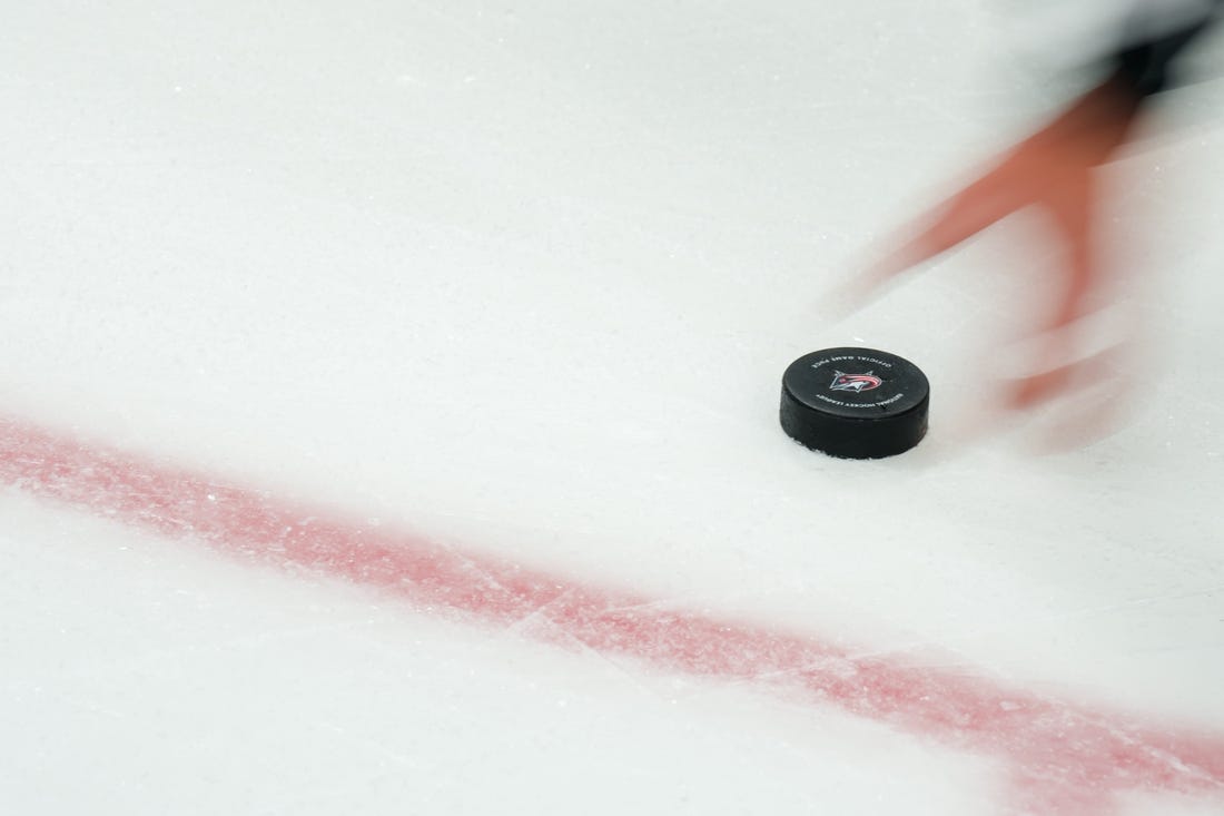 Oct 20, 2023; Columbus, Ohio, USA;  NHL referee Peter MacDougall (38) grabs the puck off the ice during the game between the Calgary Flames and the Columbus Blue Jackets in the first period at Nationwide Arena. Mandatory Credit: Aaron Doster-USA TODAY Sports