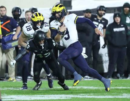 Michigan Wolverines quarterback J.J. McCarthy (9) runs by Michigan State Spartans defensive back Malik Spencer (43) during first-half action at Spartan Stadium in East Lansing on Saturday, Oct. 21, 2023.