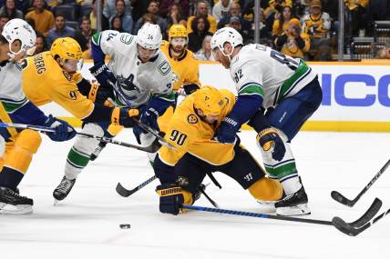 Oct 24, 2023; Nashville, Tennessee, USA; Nashville Predators center Ryan O'Reilly (90) is hit by Vancouver Canucks defenseman Ian Cole (82) as he handles the puck in front of the net during the third period at Bridgestone Arena. Mandatory Credit: Christopher Hanewinckel-USA TODAY Sports