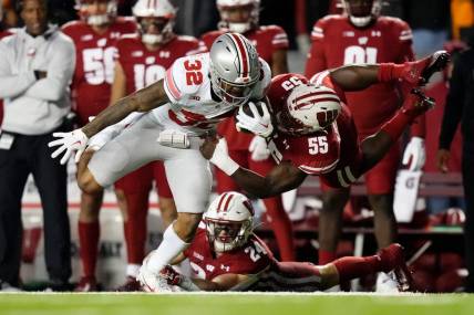 Oct 28, 2023; Madison, Wisconsin, USA; Wisconsin Badgers linebacker Maema Njongmeta (55) attempts to tackle Ohio State Buckeyes running back TreVeyon Henderson (32) during the first half of the NCAA football game at Camp Randall Stadium.