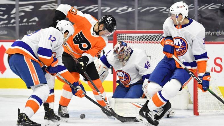 Jan 30, 2021; Philadelphia, Pennsylvania, USA; Philadelphia Flyers left wing Oskar Lindblom (23) battles for the puck with New York Islanders left wing Matt Martin (17) and defenseman Adam Pelech (3) in front of goaltender Semyon Varlamov (40) during the second period at Wells Fargo Center. Mandatory Credit: Eric Hartline-USA TODAY Sports