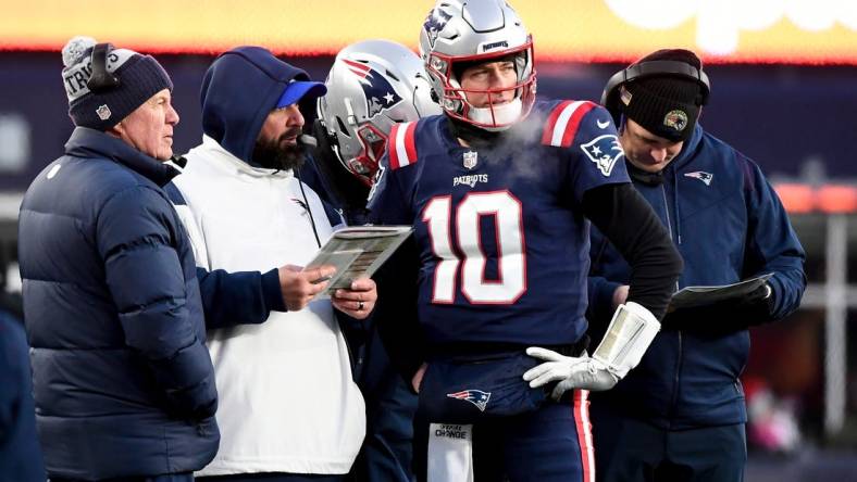 Dec 24, 2022; Foxborough, Massachusetts, USA; New England Patriots quarterback Mac Jones (10) checks with head coach Bill Belichick, left, and senior football advisor Matt Patricia, second from left, during the second half against the Cincinnati Bengals at Gillette Stadium. Mandatory Credit: Eric Canha-USA TODAY Sports