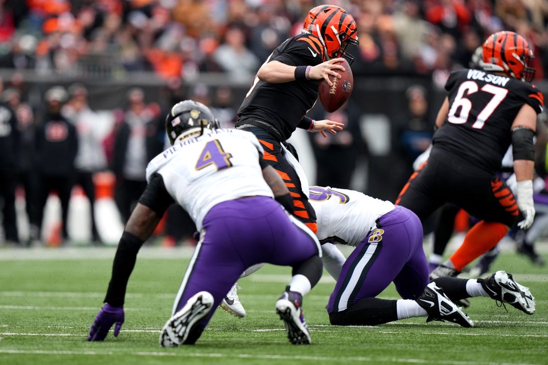 Jan 8, 2023; Cincinnati, Ohio, USA; Cincinnati Bengals quarterback Joe Burrow (9) avoids pressure by Baltimore Ravens linebacker Jason Pierre-Paul (4) in the first quarter at Paycor Stadium. Mandatory Credit: Kareem Elgazzar-USA TODAY Sports