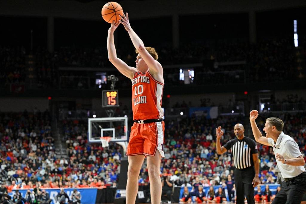 Mar 16, 2023; Des Moines, IA, USA; Illinois Fighting Illini guard Luke Goode (10) shoots the ball as Arkansas Razorbacks head coach Eric Musselman reacts during the first half at Wells Fargo Arena. Mandatory Credit: Jeffrey Becker-USA TODAY Sports